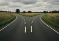 A fork in the road surrounded by fields.