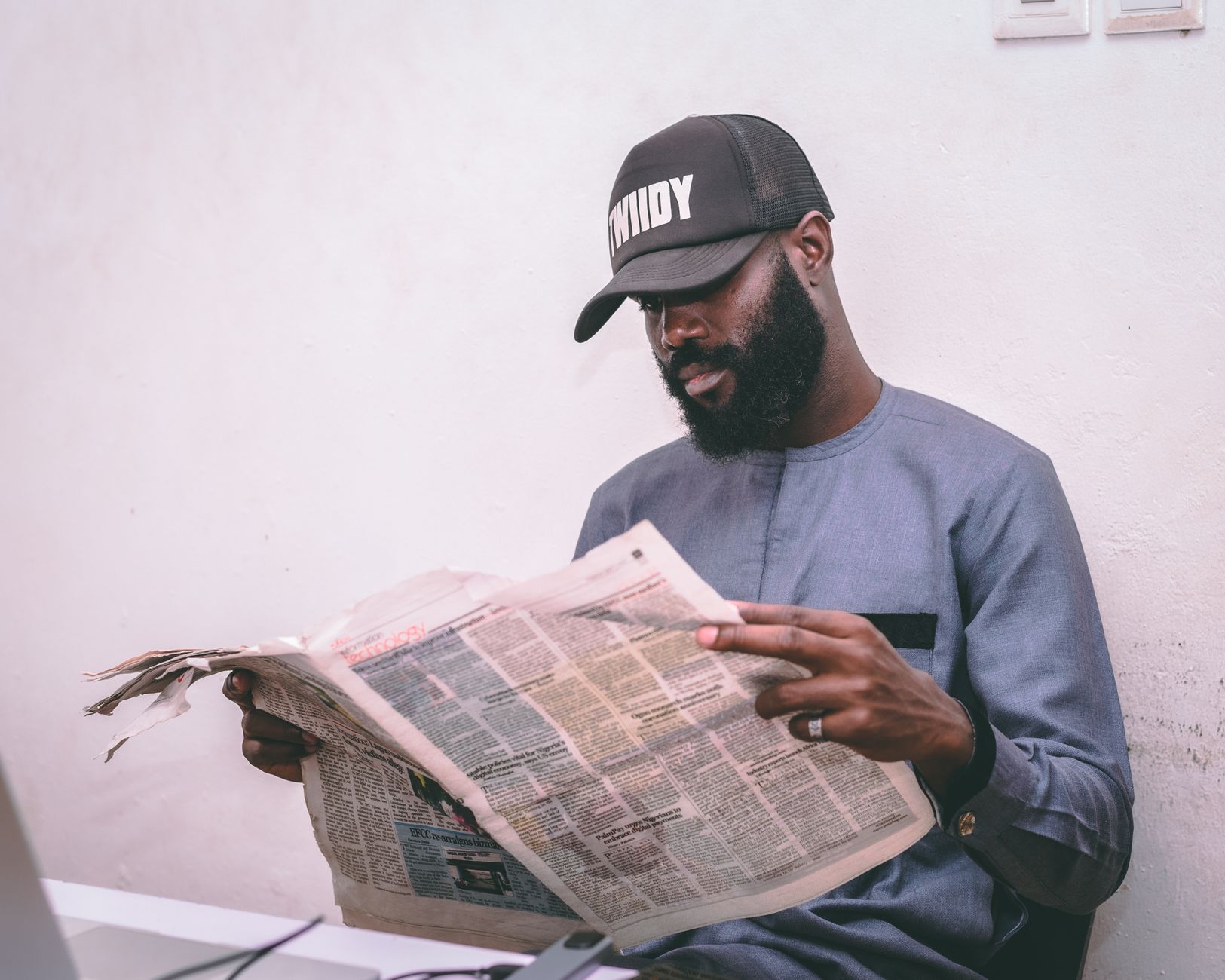 Adult man reading a newspaper indoors, wearing a cap and traditional attire. — Mastering SEO: Strategies to Boost Online Visi